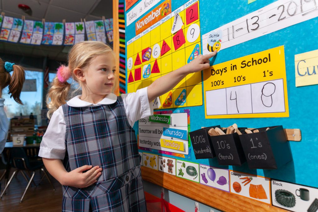 A student at a private kindergarten in Columbia, MD, learns about using a calendar and builds her confidence in front of the class.